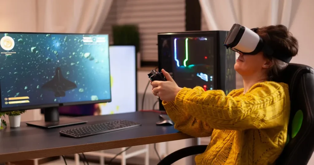 Woman wearing VR headset and yellow sweater playing Tech Etruesports games with VR controllers at dual monitor gaming desk setup