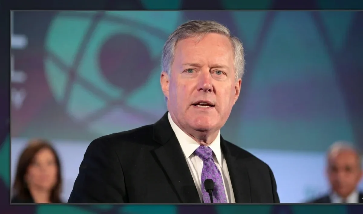 Mark Meadows speaking at a podium, former White House Chief of Staff requesting DOJ reimbursement for legal fees.