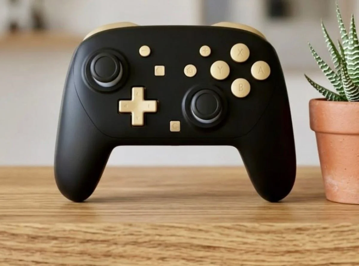 Steam Controller with black body and gold buttons placed on a wooden table