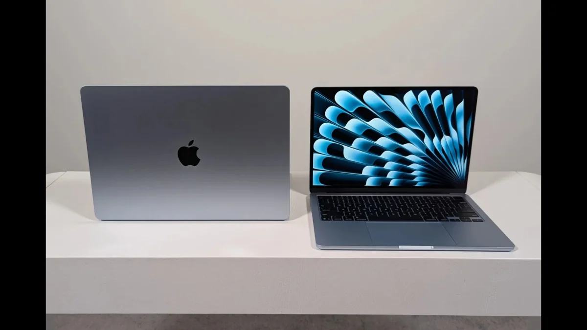 A side-by-side comparison of two MacBook laptops on a white desk, showing the Midnight finish with the Apple logo and the Starlight model open with a vibrant Liquid Retina display.