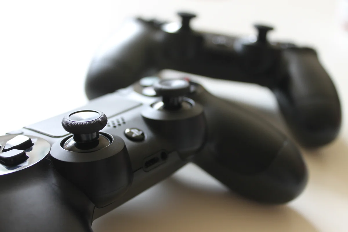 A close-up studio shot of the iconic original grey Sony PlayStation PS1 controller, highlighting its classic d-pad and directional buttons.