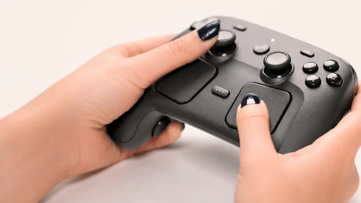 Close-up of a Steam Controller held in both hands, showing analog sticks, touchpad, and buttons in a clean, softly lit product-style shot with no text or overlays.